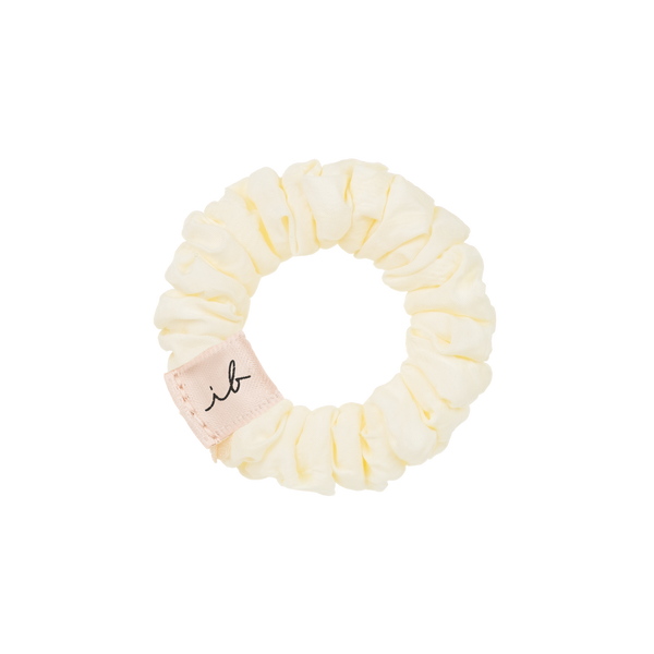 Cream-colored fabric hair scrunchie with a small "ib" tag, part of the LOOP 3 pc | invisibobble collection designed for gentle hair care and stylish wellness accessory.