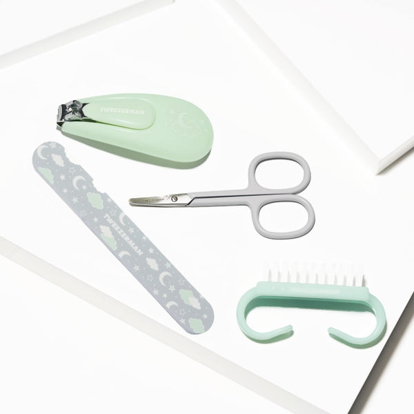 Baby Manicure Kit | Tweezerman featuring a mint green nail clipper, gray baby scissors, a patterned nail file, and a small nail brush designed for gentle baby skincare.