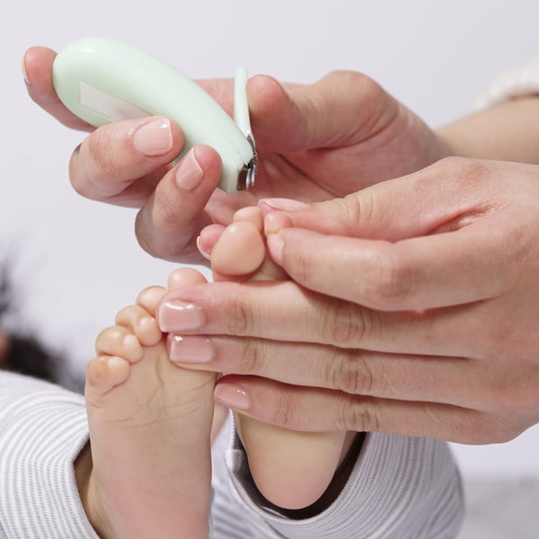 Woman gently trimming a baby's toenails using the Baby Manicure Kit | Tweezerman with a soft green ergonomic handle for safe and comfortable nail care.